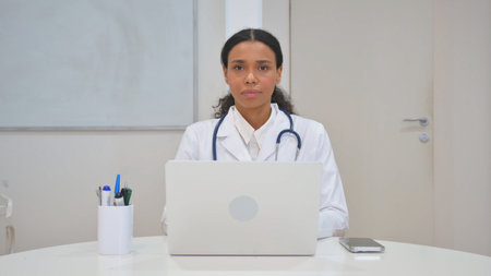 African Doctor Looking at Camera while Working on Laptopの写真素材