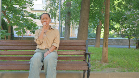 Multi Ethnic Woman Coughing on a Park Benchの写真素材