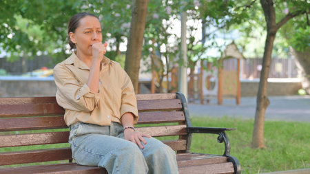 Young Woman Coughing on a Park Bench