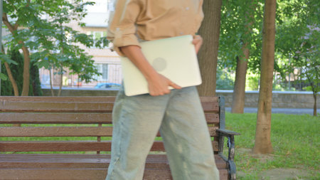 Multi Ethnic Woman Walking Away from Bench with Laptopの写真素材