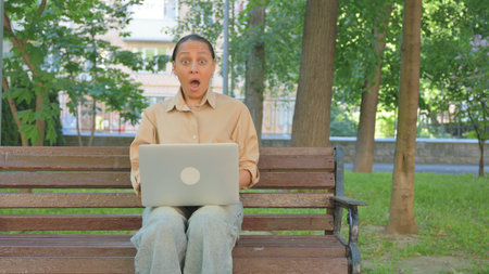Multi Ethnic Woman Reacting with Surprise While Using Laptopの写真素材