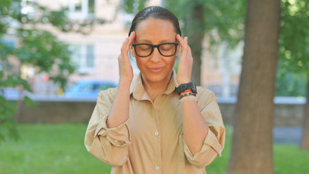 Troubled Multi Ethnic Woman with Headache Outdoorsの写真素材