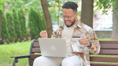 Young Multi Ethnic Man Enjoying Online Shopping with Laptop in Parkの写真素材