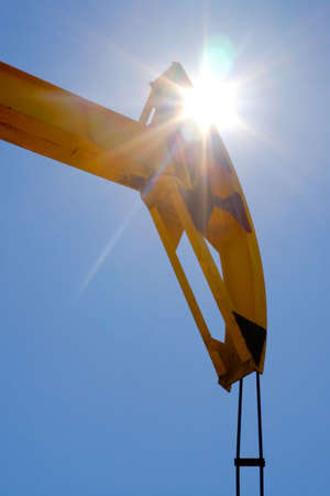 A pumpjack silhouetted against a sunrise. Sun Shining Through A Pumpjackの写真素材