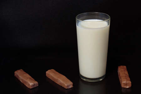 Milk in a glass and chocolate lying nearby on a dark background!の写真素材