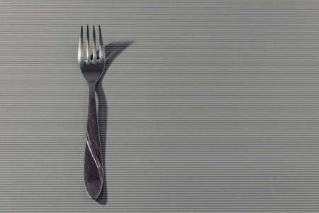 Fork with shadow on a light background with side light.の写真素材
