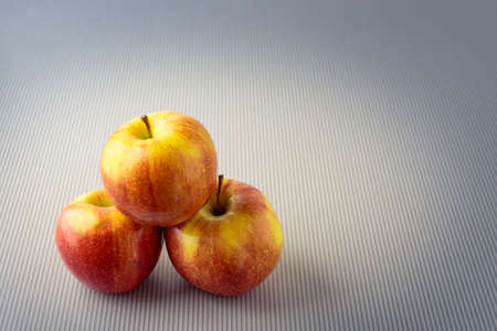 Group of three whole red apples isolated on a light background.