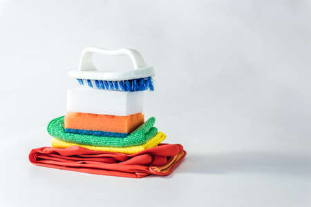 Cleaning products - brush, gloves, sponges and rags stacked on a light background.