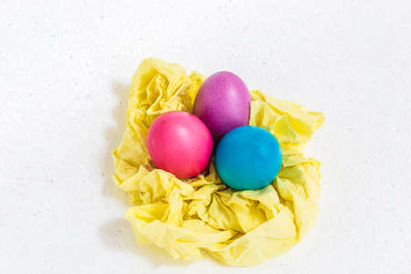 Easter eggs lie on a yellow paper substrate, isolated on a white background.の写真素材