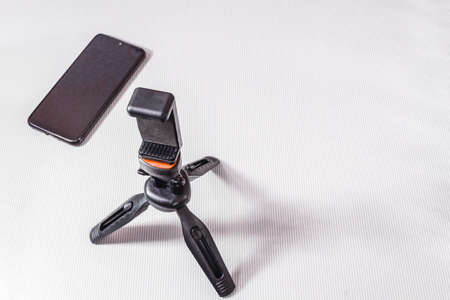 Tripod and smartphone in a bundle, for photo and video, on a light background.の写真素材