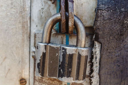 Old padlock on a metal gate to prevent burglary and penetration. Well-established security tools.の写真素材