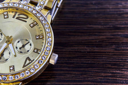 Gilded wristwatch for women with studio lighting, lying on a dark background.の写真素材