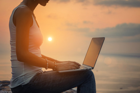 Lady with a laptop on the beach on the sunsetの写真素材