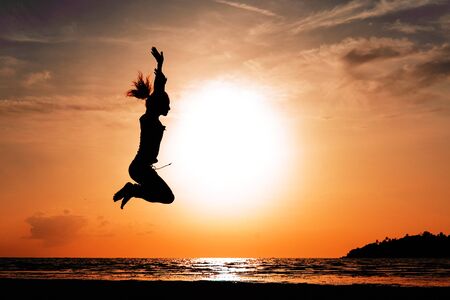Happy woman jumping against beautiful sunset. Freedom, enjoyment concept.の写真素材