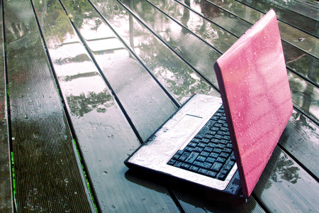 Laptop on wet floor under rainの写真素材