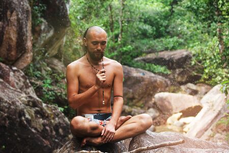 Yogi in lotus pose is sitting on the stone in jungleの写真素材