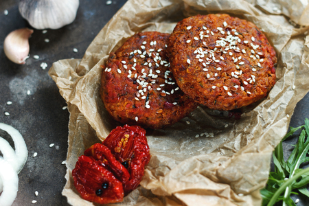 Potato burgers on baking paper on dark grey table. Still life of cooked batat burgers. Vegan food. Top viewの写真素材