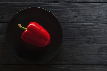 fresh red peppers on dark plate over old wooden textured background.の写真素材