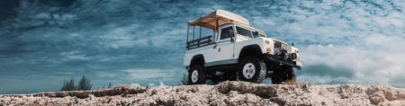 Panoramic photo of safari car on offroad , adventure trail. On high, Bottom view, sky and clouds on background, With empty space for logo or text