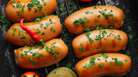 Fried sausages with herbs and vegetables in grill pan close upの写真素材