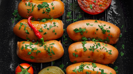 Fried sausages with herbs and vegetables in grill pan close upの写真素材