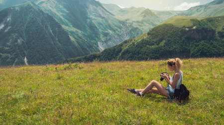 Hipster young girl photographer with backpack in amazing landscape on peak of foggy mountainの写真素材