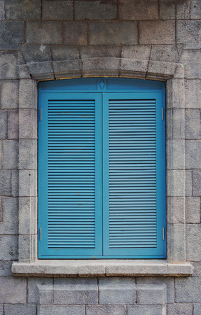 Blue wooden shutters with rustic stone wall.の写真素材