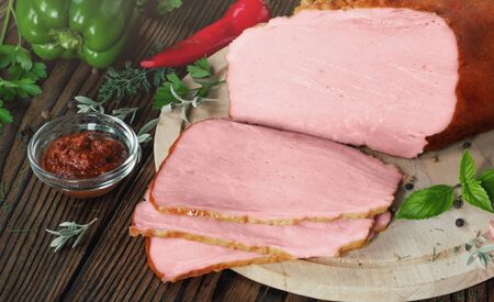 Sliced smoked brisket with sauce and vegetables on wooden backgroundの写真素材