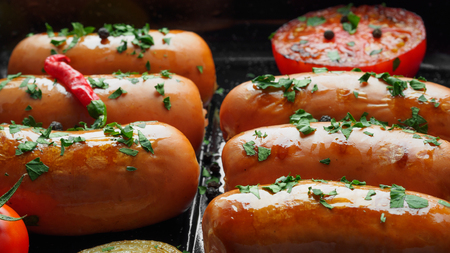 Fried sausages with herbs and vegetables in grill pan close upの写真素材