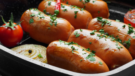 Fried sausages with herbs and vegetables in grill pan close upの写真素材