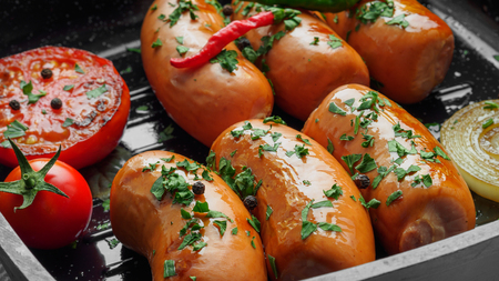 Fried sausages with herbs and vegetables in grill pan close upの写真素材