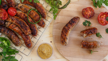 Grilled sausages and vegetables on a wooden background in rustic style. Top view. Flat lay.の写真素材
