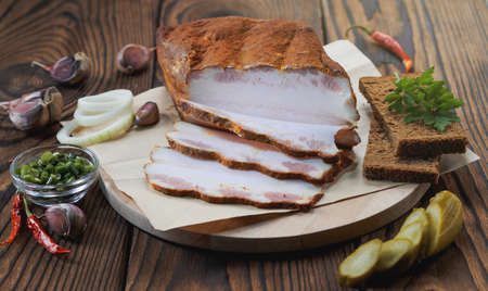 Fresh sliced bacon with dill branch, cucumber and rye bread on the wooden backgroundの写真素材