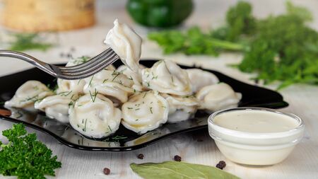 Meat dumplings - russian pelmeni, ravioli with meat on a black plate on a wooden backgroundの写真素材