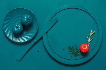 Painted Turquoise plate, cutlery and tomatoes on the turquoise background, emphasis on red tomatoの写真素材