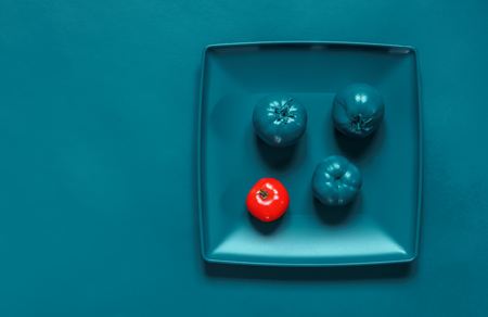 Painted Turquoise plate and tomatoes on the turquoise background, emphasis on red tomatoの写真素材