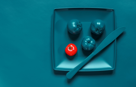 Painted Turquoise plate, cutlery and tomatoes on the turquoise background, emphasis on red tomatoの写真素材