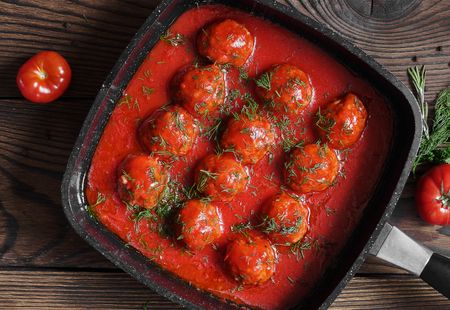 Meatballs with spicy tomato sauce in pan. horizontal view from above, on wooden backgroundの写真素材