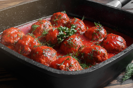 Meatballs with spicy tomato sauce in pan on wooden backgroundの写真素材
