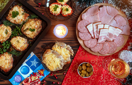 Christmas baked chops with cheese and cold cuts platter, served on the old wooden table with a red tablecloth top viewの写真素材