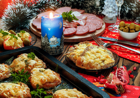 Christmas baked chops with cheese and cold cuts platter, served on the old wooden table with a red tableclothの写真素材