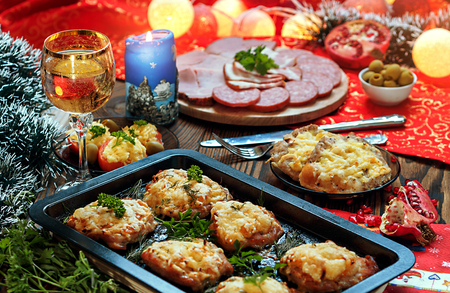 Christmas baked chops with cheese and cold cuts platter, served on the old wooden table with a red tableclothの写真素材