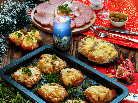 Christmas baked chops with cheese and cold cuts platter, served on the old wooden table with a red tableclothの写真素材