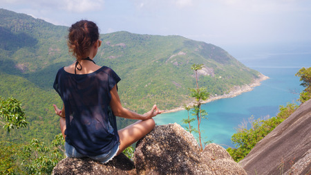 girl in yoga pose with picturesque view of the island at a height. viewpointの写真素材