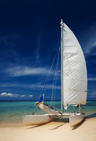 Sail boat, catamaran, on tropical beach with blue waterの写真素材