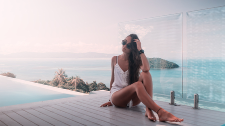 A beautiful fashionable girl in a luxury villa with picturesque view behindの写真素材