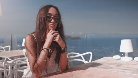 A beautiful fashionable girl in a luxury restaurant with picturesque view behindの写真素材