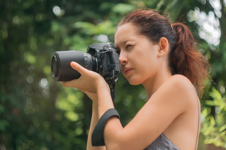 Woman is a professional photographer with dslr camera, soft focus, natural bokeh