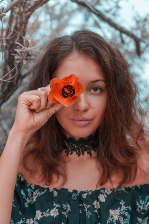 young woman holding orange flower on her eyeの写真素材