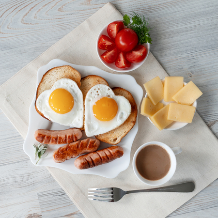 Breakfast with love - fried eggs in the shape of a heart, fried sausages and coffeeの写真素材